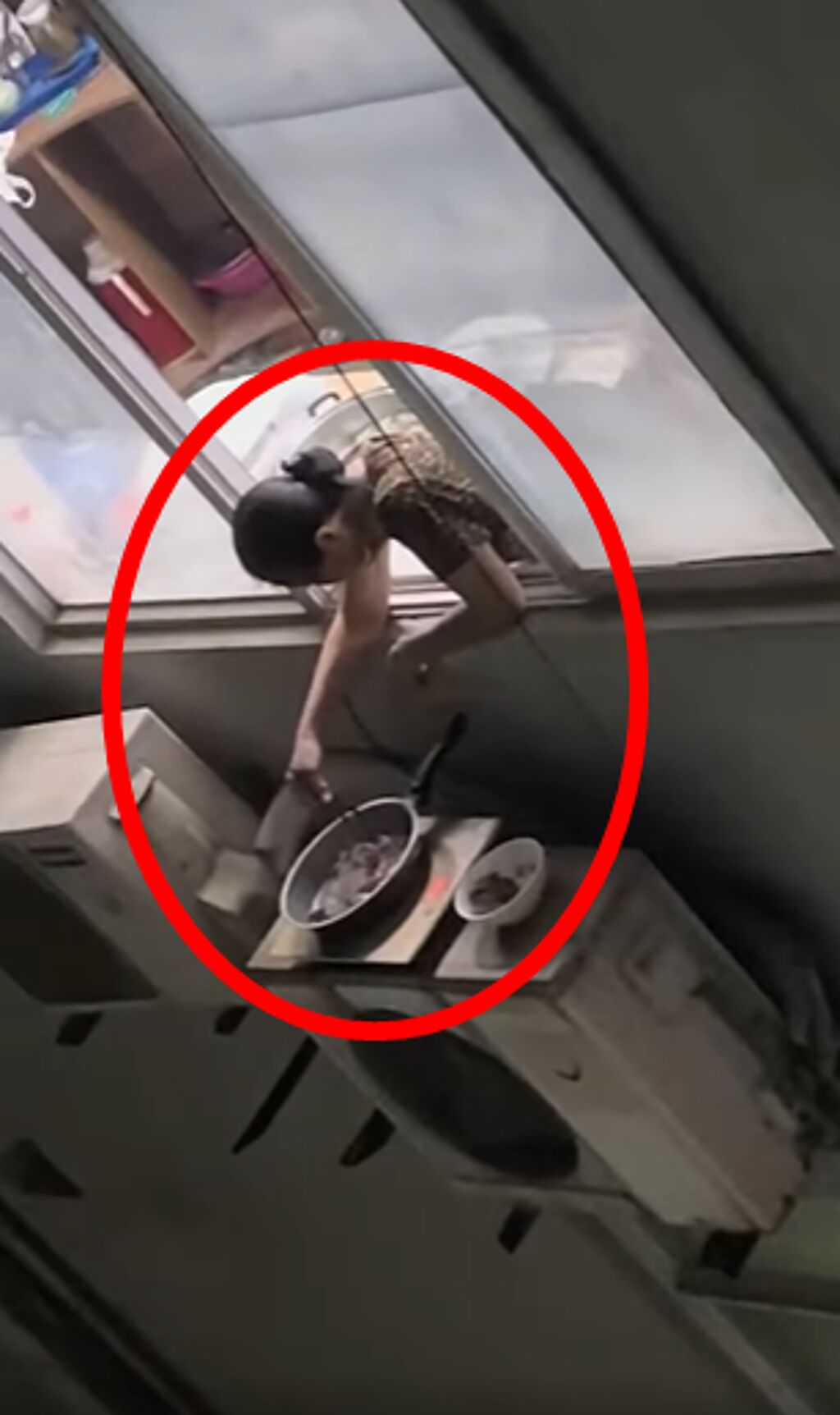 1名女網友被目擊在高樓層的住家，頭伸出窗外在「煮飯」，原來她把電磁爐和鍋具放在冷氣室外機的上方。（翻攝自臉書「爆廢公社」）