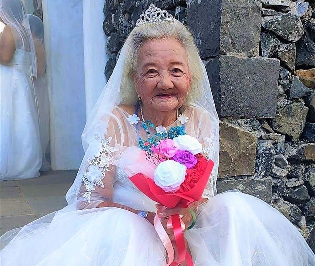 高齡92歲的何阿嬤家住澎湖七美西湖村，從沒穿過白色婚紗的她，拍照時笑得好開心。（呂汶駿提供）