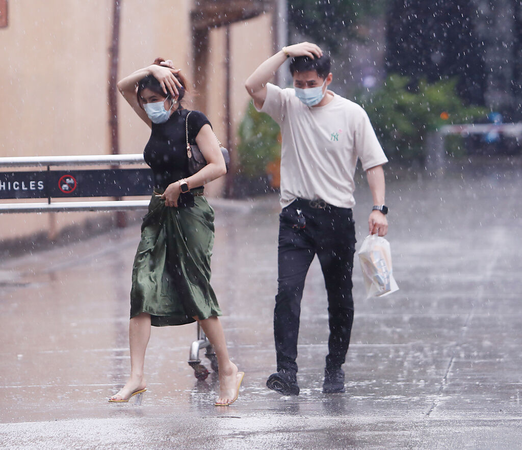中央氣象局25日發布大雨特報。午後大雨傾盆，外出民眾沒帶雨具，只能先用手遮擋。(陳怡誠攝)