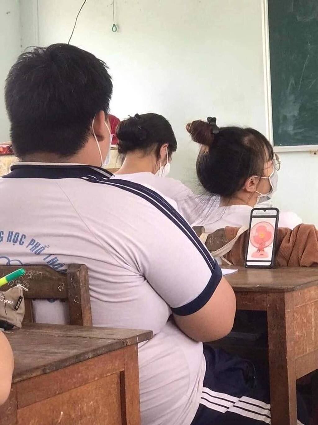 越南有位國中男學生在桌上擺「手機」，其手機放著1張電風扇照片，也讓網友笑翻「望扇乘涼」。（翻攝自臉書爆廢公社公開版）