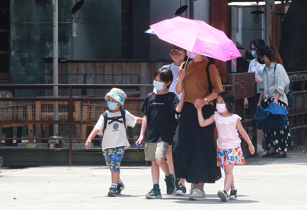 中午時分民眾帶著小朋友外出，撐著傘避免太陽直曬。（陳信翰攝）
