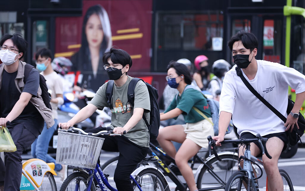 天氣炎熱，民眾仍戴口罩騎乘腳踏車，指揮中心今宣布騎車免戴口罩。（羅永銘攝）