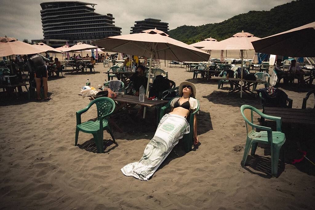 焦曼婷披了條紙鈔被子，在海邊的躺椅大曬日光浴。(圖/焦曼婷 FB)