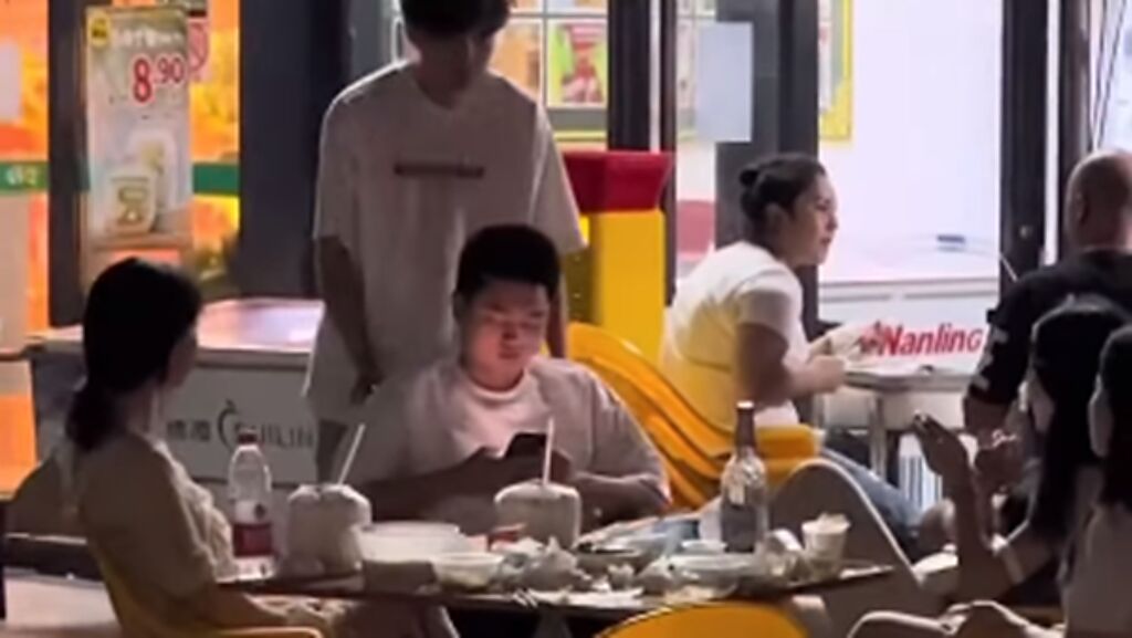 一名坐輪椅的男子低頭滑手機被朋友惡作劇，朋友推著他到戶外餐廳，讓他和3名不認識的長腿妹子坐一桌。（圖／翻攝自爆廢公社公開版）