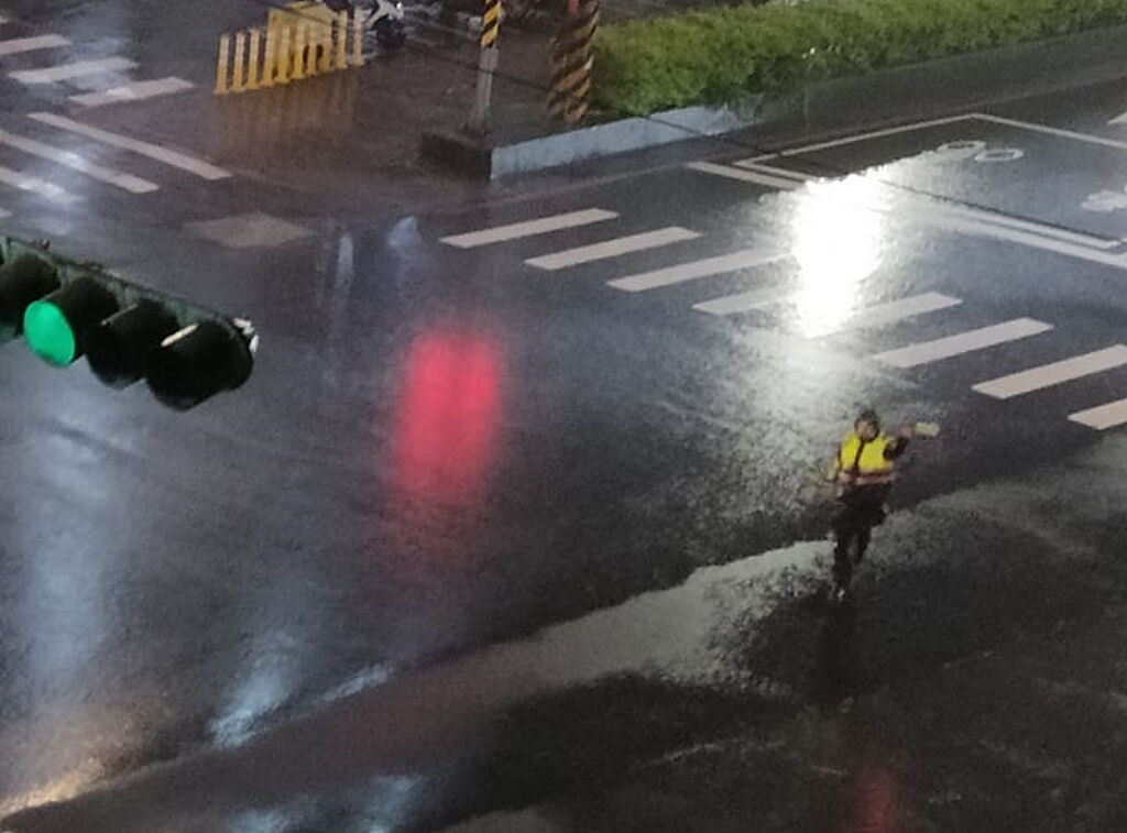汐止1名民眾昨晚（15）在路口發現1名員警頂著強風驟雨指揮交通，過了4小時後，該民眾見到同一名員警仍持續指揮，讓他大感心疼。（翻攝自臉書「汐止集團」）