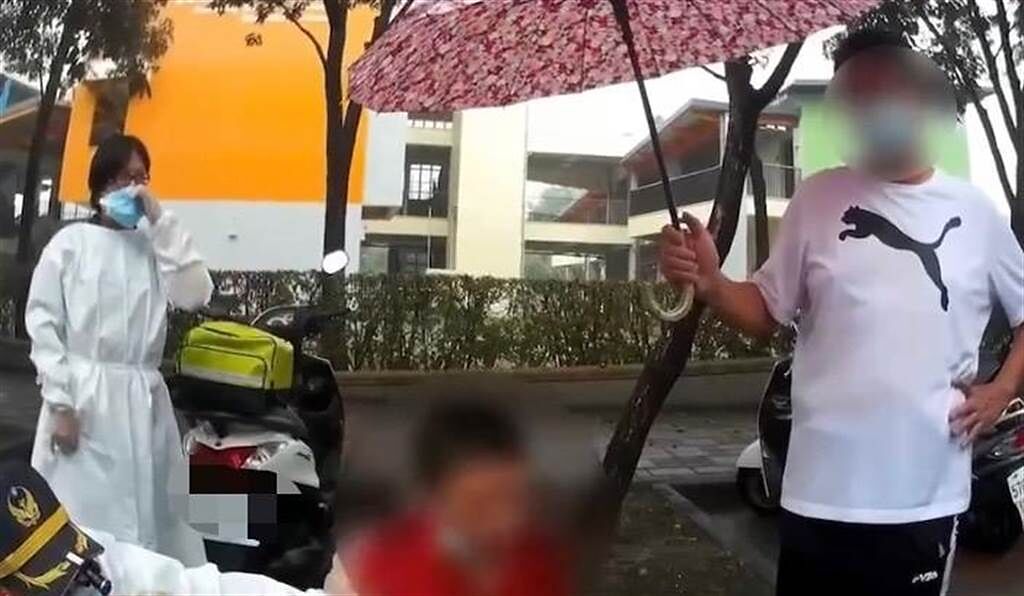 高雄市岡山區一名男子10月31日路倒，警消到場處理，民眾為路倒的男子撐傘。（翻攝照片／林瑞益高雄傳真）