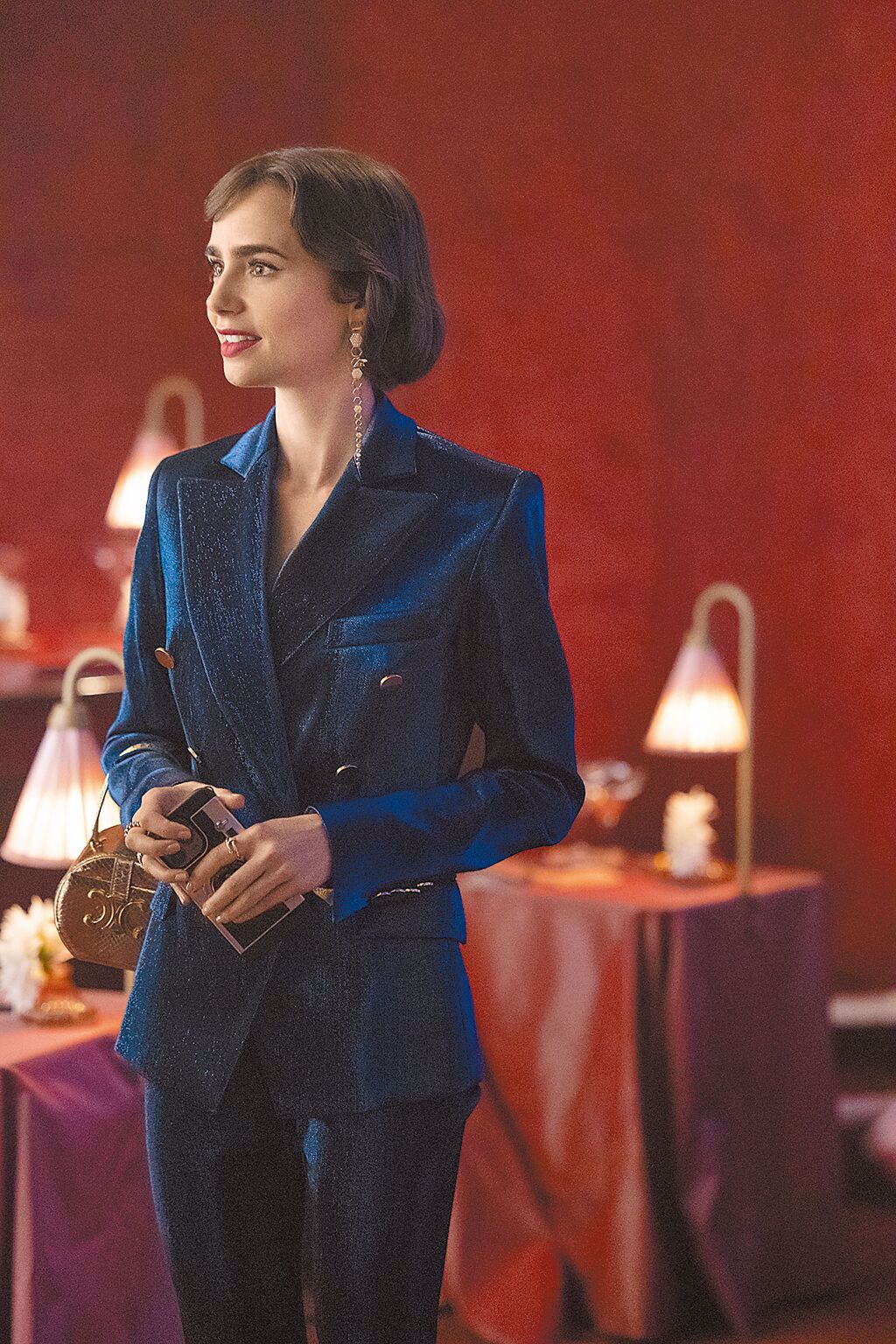 艾蜜莉以Balmain藍色天鵝絨西裝外套搭配Celine包款，展現華貴氣質。（Netflix提供）