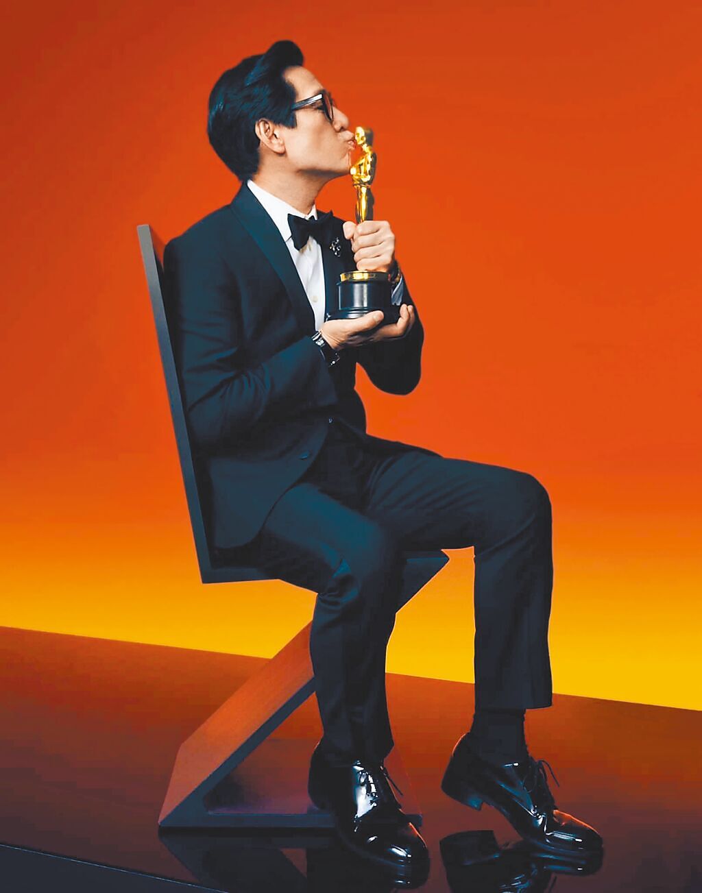 奧斯卡最佳男配角關繼威穩坐於Zig-Zag單椅上，開心親吻小金人。（摘自美國影藝學院官網）